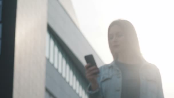 Nainen käyttää älypuhelinta ulkona
 - Materiaali, video