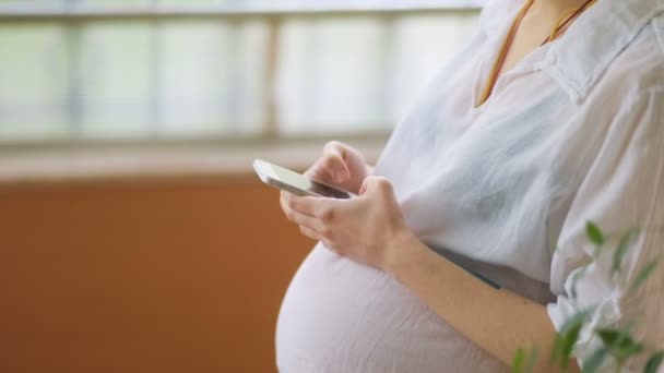 Terhes nő okos telefont használ - Felvétel, videó