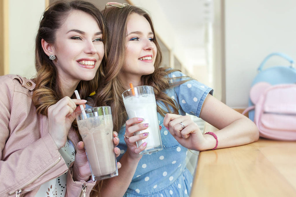 Two beautiful young women in a cafe drinking coctails and laughi - Photo, Image