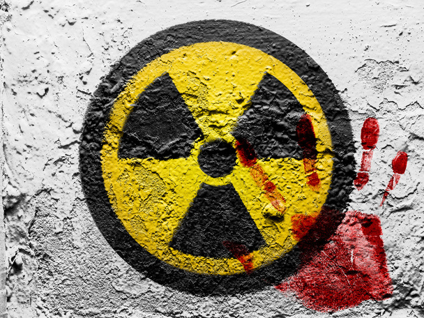 Símbolo de radiación nuclear pintado en la pared grunge con una huella de palma ensangrentada
 - Foto, Imagen