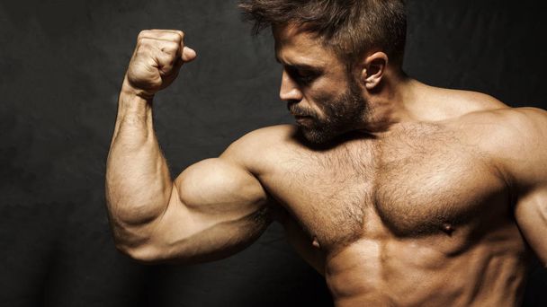 Bodybuilder flexing biceps - 写真・画像