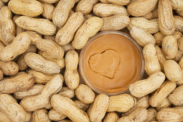 Mantequilla de cacahuete y cacahuetes crudos en cáscaras
 - Foto, Imagen