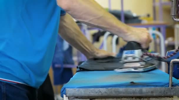 Nahaufnahme eines Arbeiters beim Bügeln von Kleidung in einer Textilfabrik - Filmmaterial, Video