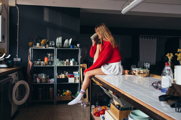 Beautiful blonde woman rests on kitchen counter - Valokuva, kuva