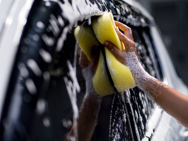 Γυναίκα χέρι με κίτρινο σφουγγάρι πλυσίματος αυτοκινήτων - Φωτογραφία, εικόνα