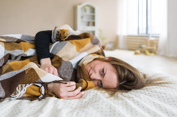 Πορτρέτο του όμορφη νεαρή γυναίκα ξαπλωμένη στο κρεβάτι στο σπίτι - Φωτογραφία, εικόνα