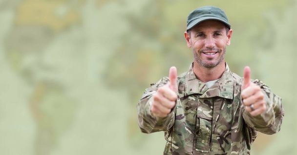 Soldier thumbs up against blurry map with green overlay - Фото, изображение