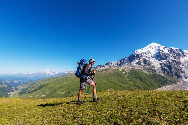 Турист идет вдоль зеленых холмов
  - Фото, изображение