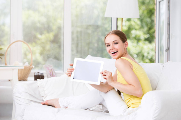 Happy woman in the living room showing an electronic tablet. - Foto, afbeelding