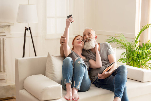 Mature couple with digital devices  - Фото, изображение