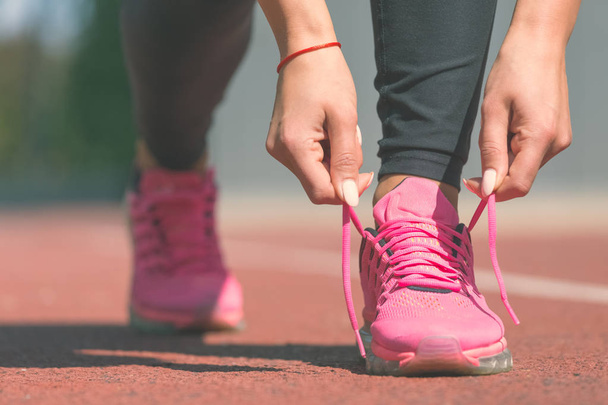 Woman tying laces of running shoes before training  - Foto, imagen