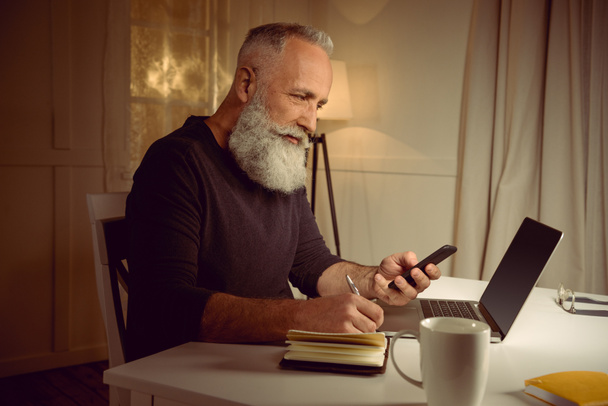 szürke hajú férfi munka otthon - Fotó, kép