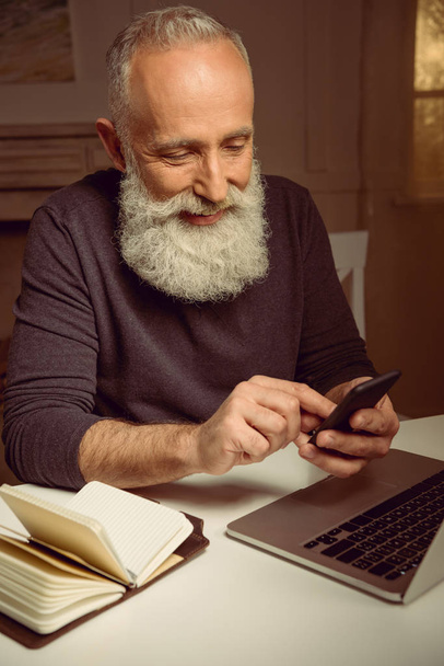 Улыбающийся мужчина с помощью смартфона дома
 - Фото, изображение