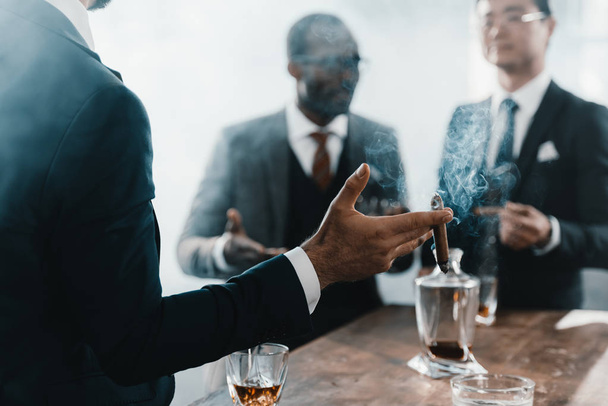 businessman smoking cigar with multicultural business team spending time behind - Foto, Imagen