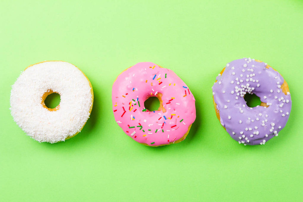 Colorful round donuts on green background. Flat lay, top view. - Fotografie, Obrázek