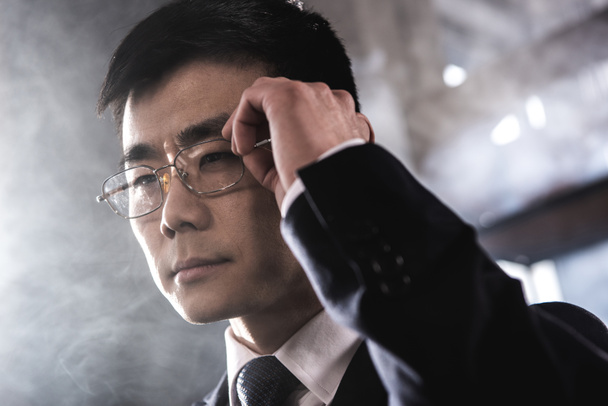 Portrait d'homme d'affaires asiatique confiant dans des lunettes détournant les yeux
 - Photo, image