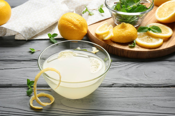 Delicious lemon juice in bowl on wooden background - Φωτογραφία, εικόνα