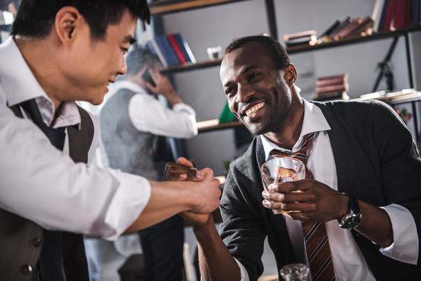 cheerful colleagues drinking alcohol while spending time together after work - Photo, Image