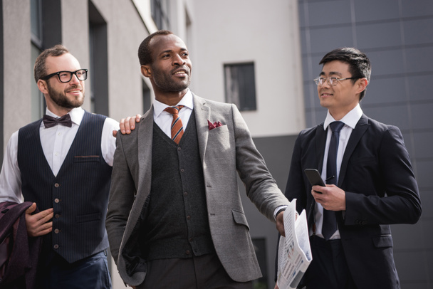 young stylish multiethnic businessmen in formalwear walking outdoors, business team meeting - Zdjęcie, obraz