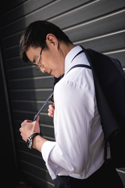 joven elegante asiático hombre de negocios en gafas de pie al aire libre
 - Foto, Imagen