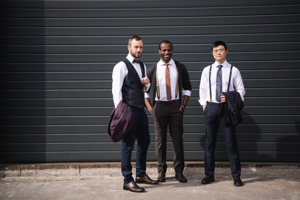 giovani uomini d'affari multietnici alla moda in abbigliamento formale in piedi all'aperto, riunione del team di lavoro
 - Foto, immagini