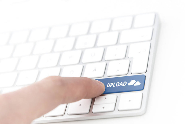 Finger drücken eine grüne Taste mit der Aufschrift Upload mit Cloud-Symbol auf einer Computertastatur - Foto, Bild