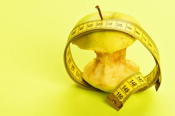 Circle of measuring tape and bitten apple in it - Foto, afbeelding