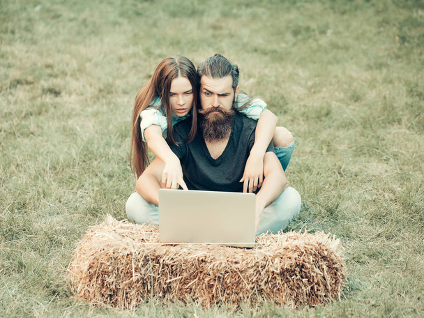 people, brutal man and pretty girl using laptop on nature - Zdjęcie, obraz