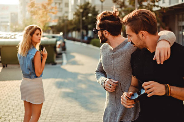 Друзья мужчины смотрят на девушку на улице
 - Фото, изображение