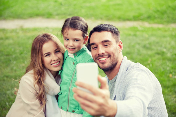 happy family taking selfie by smartphone outdoors - Fotografie, Obrázek