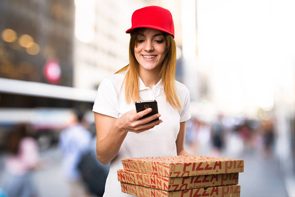 Pizza delivery woman talking to mobile  on unfocused background - Photo, Image