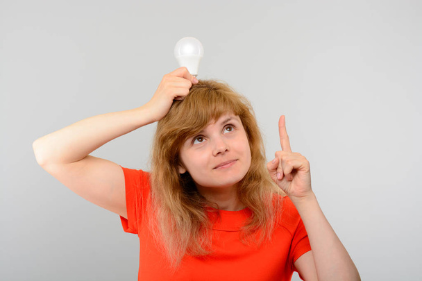 Donna che tiene la lampadina sopra la testa
 - Foto, immagini