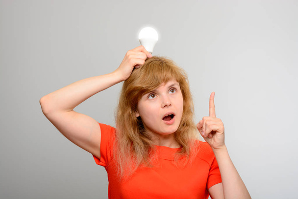 Woman holding light bulb over head - 写真・画像