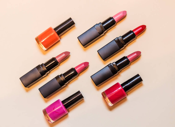 Set of lipsticks and nail polishes on beige background - 写真・画像