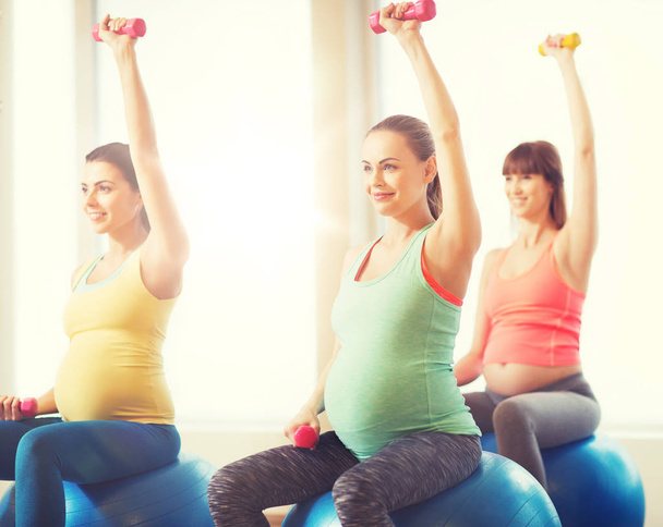 happy pregnant women exercising on fitball in gym - Foto, Imagem
