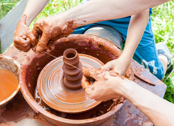 Teacher helps his student to work with red clay. Work on the pot - Photo, Image