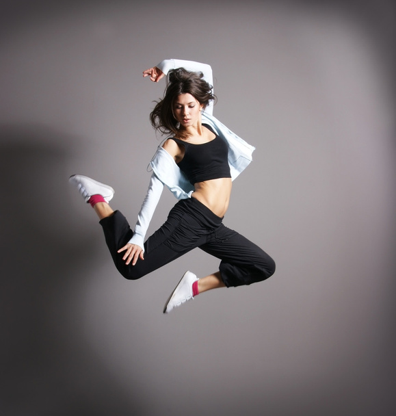 Young and sexy modern dancer over grey background - 写真・画像