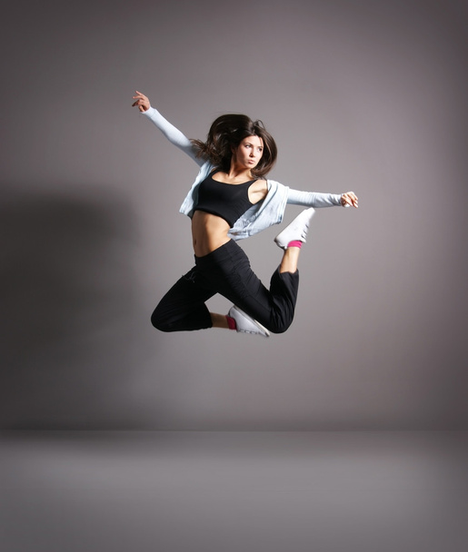 Young and sexy modern dancer over grey background - Foto, Imagem
