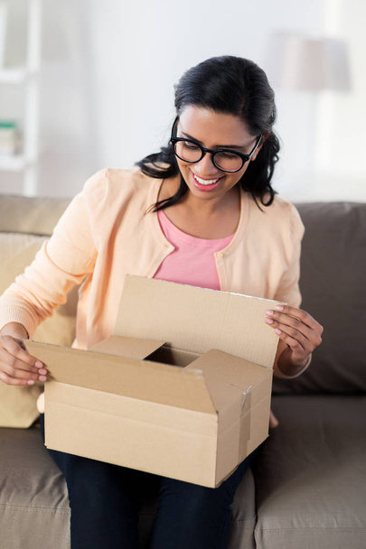 happy young indian woman with parcel box at home - Foto, Bild
