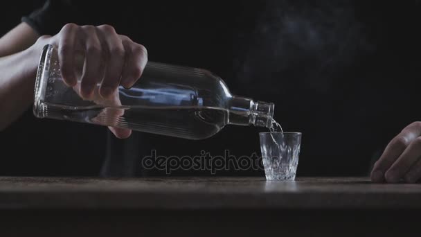 Concept van alcoholisme. Man giet van alcohol in een glas en drinkt in een donkere kamer in slow-motion - Video