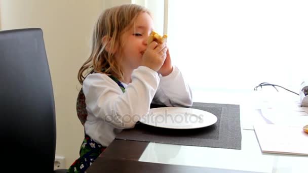 Niña vestida a rayas sentada en una mesa, comiendo panqueques con mousse de manzana o mermelada y canela
 - Imágenes, Vídeo