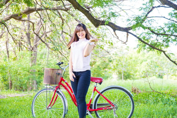 Ázsiai fiatal nő gyönyörű piros kerékpárt egy parkban.  - Fotó, kép