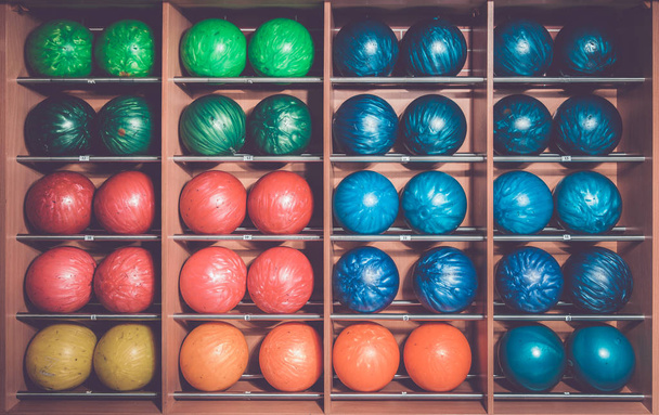 Шары для боулинга в стойке, отсортированные по размеру и цвету - Фото, изображение