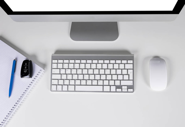 Workplace with computer and wireless keyboard and mouse, notebook and car keys on white background - Fotó, kép