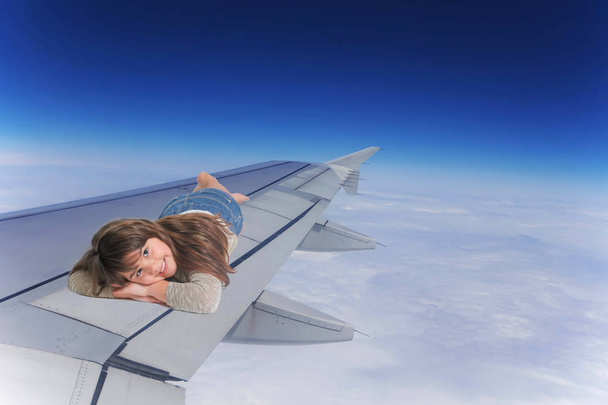 Smiling Little girl lying on the wing of an aircraft - Foto, afbeelding