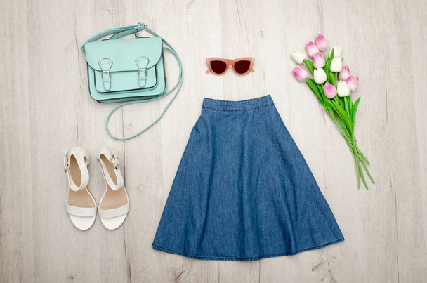 Jeans skirt, glasses, white shoes, handbag and a bouquet of tulips. Fashionable concept. Wooden background. - Photo, Image