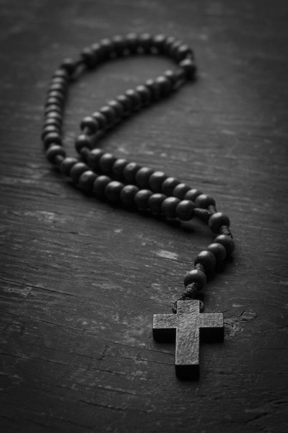 Κομπολόι με χριστιανικό σταυρό σε μονοφωνικό φόντο. Μαύρο και άσπρο φωτογραφία. - Φωτογραφία, εικόνα