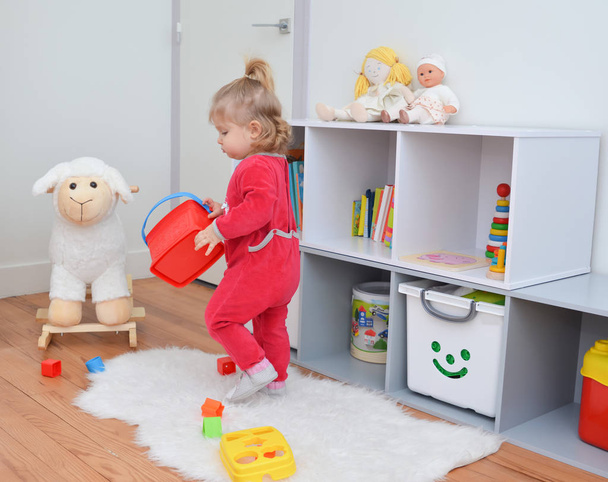 Girl playing with toys in the white children's room - Фото, изображение