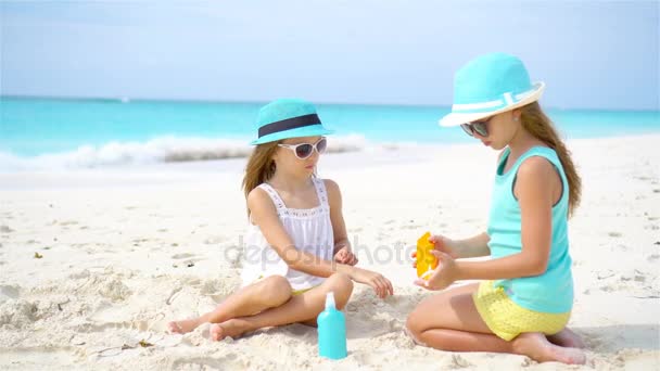 子供たちはビーチでお互いに太陽のクリームを適用します。紫外線からの保護の概念 - 映像、動画