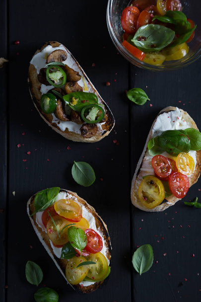Bruschetta with cherry tomatoes, cream cheese, mushrooms, basil - Foto, afbeelding